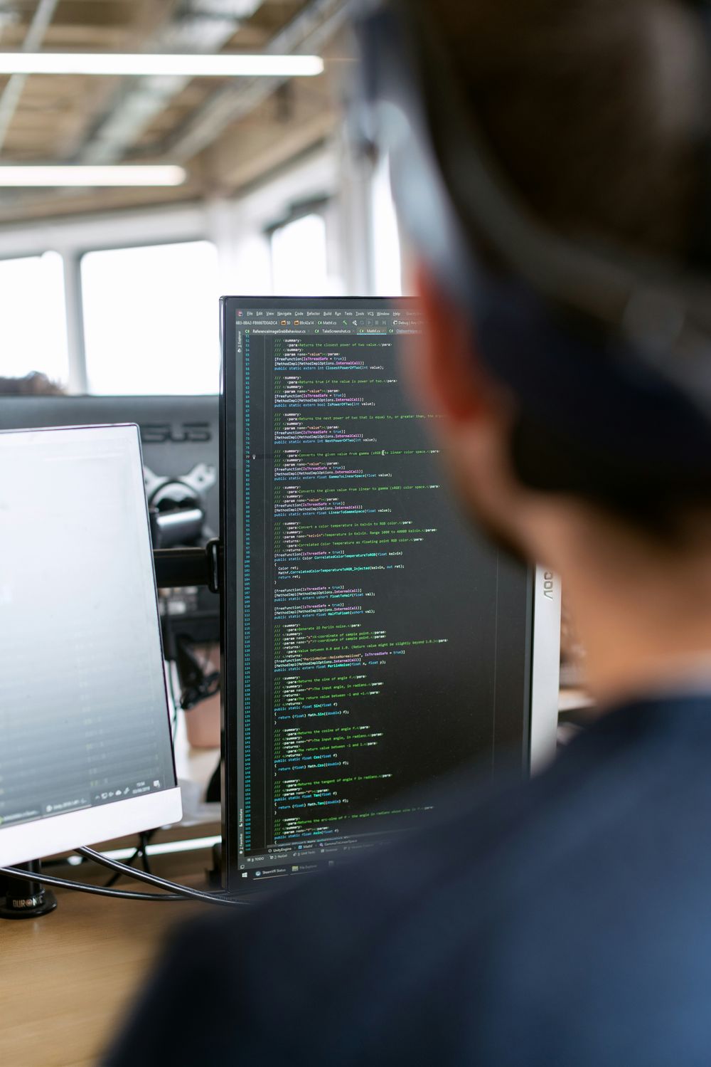 Engineer reviewing technical work across multiple monitors.