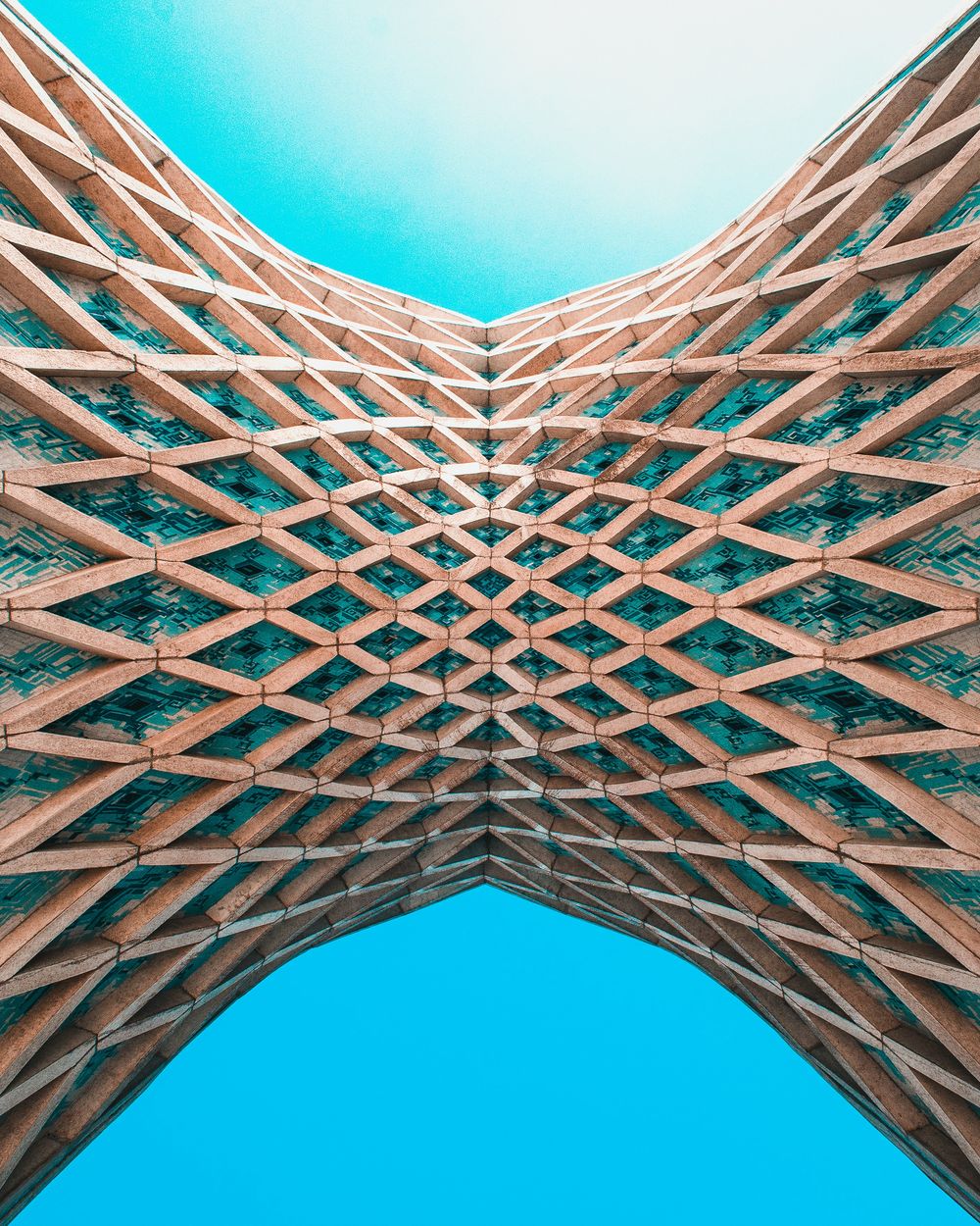 Geometric lattice structure viewed from below against a blue sky.
