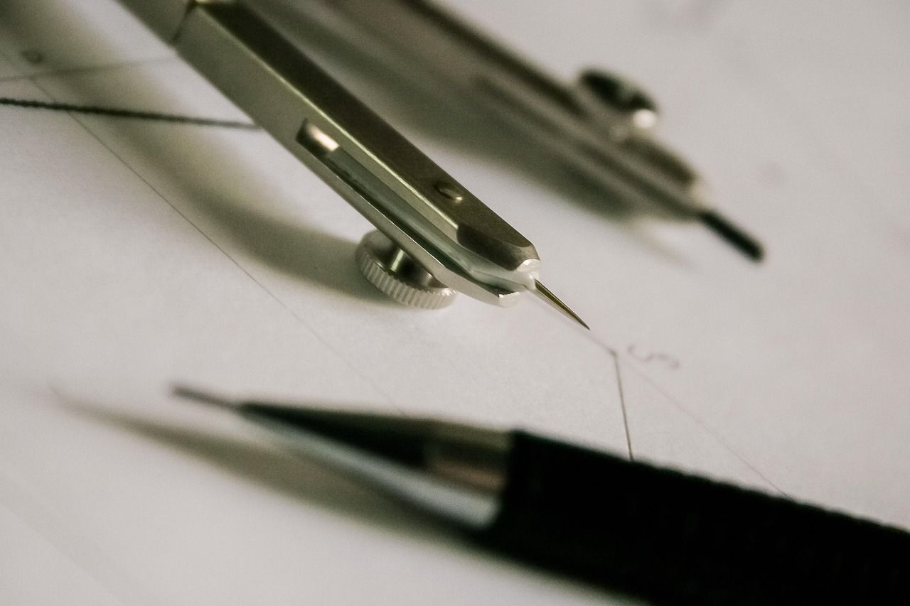 Drawing compass and mechanical pencil resting on technical drawing paper