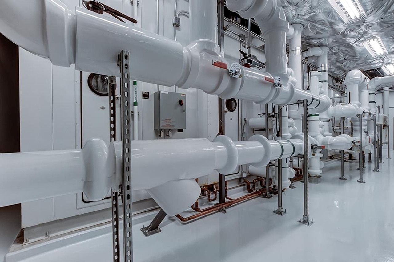 Plant room with white insulated pipework, valves and control panels